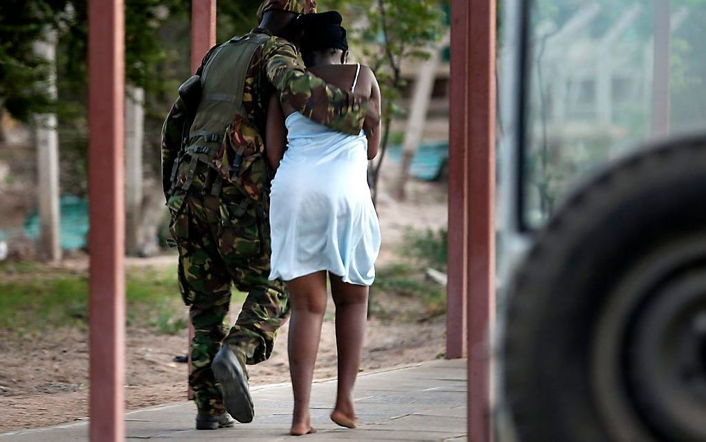 Een militair begeleidt een studente die werd bevrijd uit de universiteit in Garissa. beeld EPA