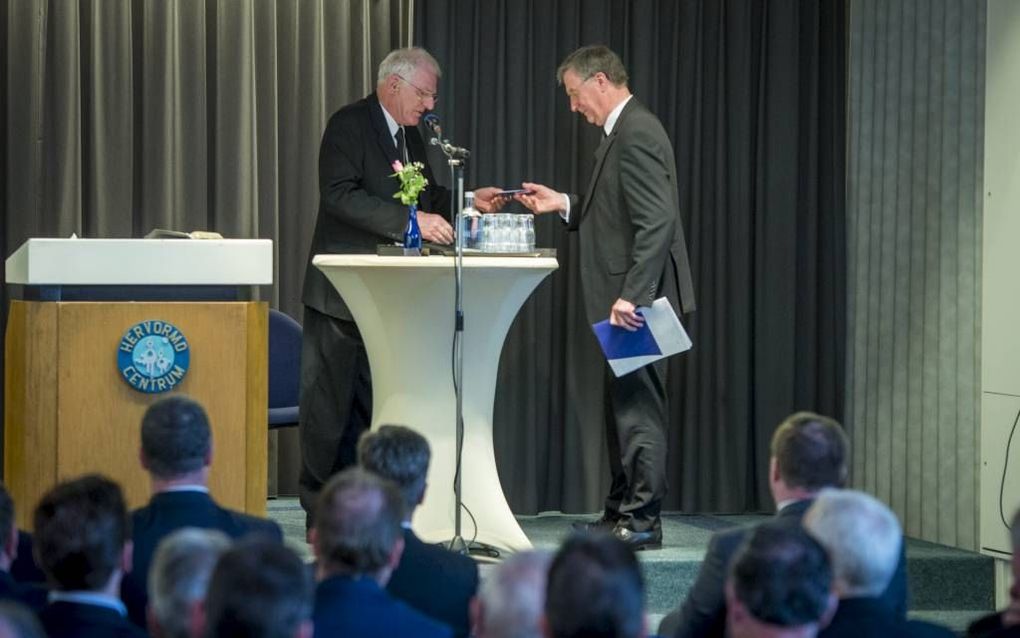 Tweede voorzitter ds. J. Schipper (links) bood zaterdag tijdens de jaarvergadering van scholenorganisatie VGS scheidend voorzitter ds. P. Mulder een geschenk aan. beeld Cees van der Wal