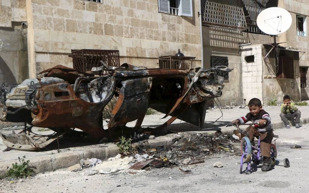 Syrische kinderen bij een uitgebrande auto, zaterdag in de Noord-Syrische stad Aleppo. Beeld AFP