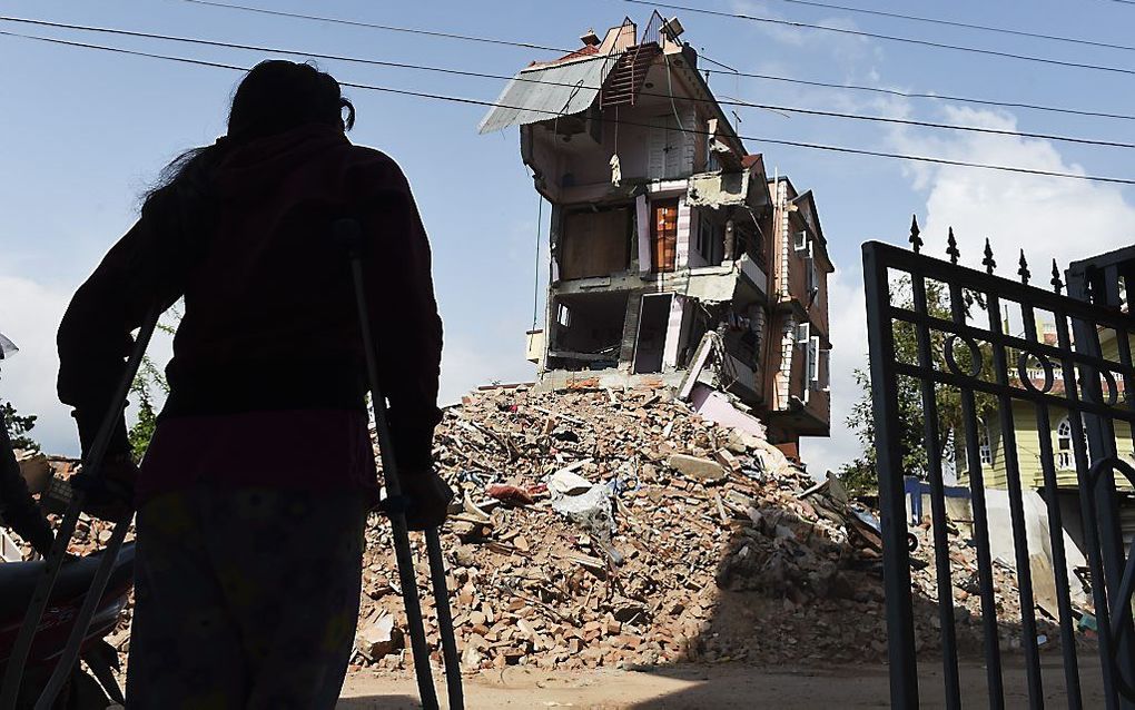 Nomita Khadka uit Kathmandu kijkt, leunend op krukken, naar haar verwoeste woning. beeld AFP