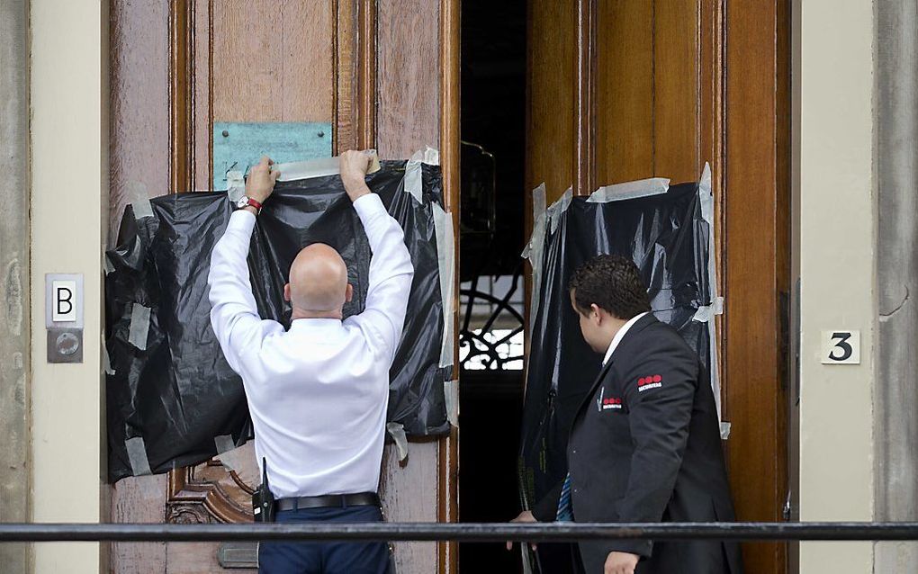 Een hakenkruis dat op de deur van het Kabinet van de Koning is geschilderd wordt met zwart zeil afgeplakt. beeld ANP