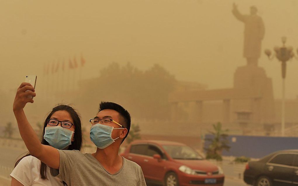 Een stel maakt een selfie in een zandstorm in Kashgar, noordwest China. beeld EPA