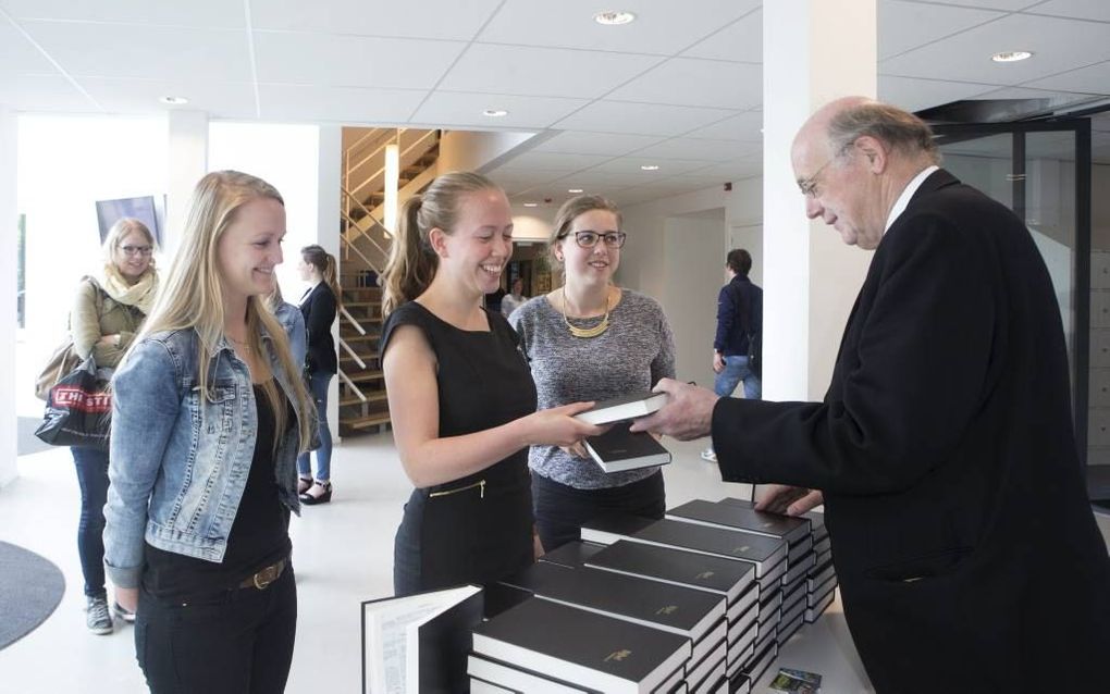 Ds. A. C. Rijken van de Gereformeerde Bijbelstichting (GBS) overhandigt een Bijbel in de Statenvertaling aan een studente van de Christelijke Hogeschool in Ede. beeld Herman Stöver