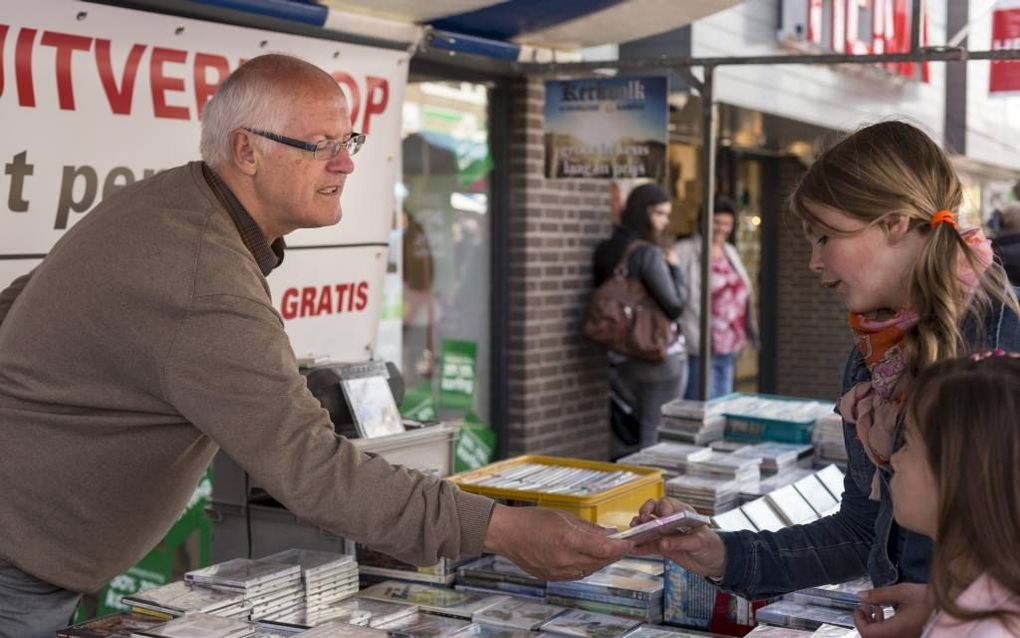 Arnold Visser (links) is met pensioen. Zijn onderneming Kerkvolk Kerkmuziek Kampen bouwt hij af. Op markten verkoopt hij dit jaar zijn resterende voorraad cd’s en dvd’s. Foto: gisteren stond Visser op de Eibertjesmarkt in Nunspeet. beeld André Dorst