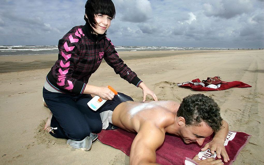 In het kader van een campagne tegen huidkanker smeerde een goed tegen de zon aangeklede actrice een badgast in Zandvoort in tegen de zon. beeld ANP