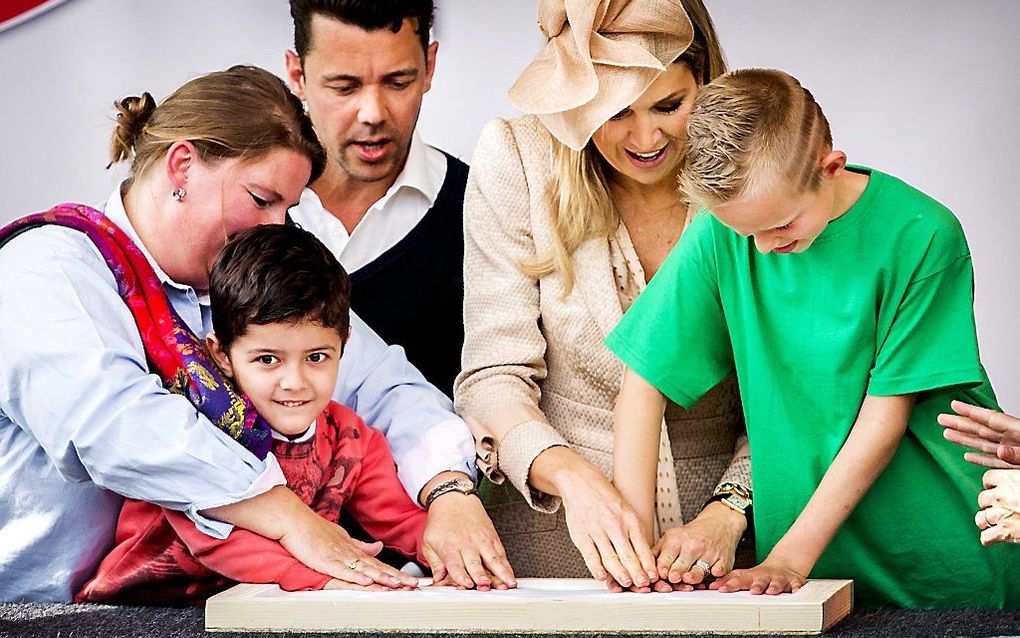 Koningin Maxima, leerling Brandon Rader (r.) en client Emir Akalin (l.) zetten hun handafdruk en openen hiermee het nieuwe Zorg Onderwijs Centrum van Koninklijke Kentalis in Zoetermeer. beeld ANP