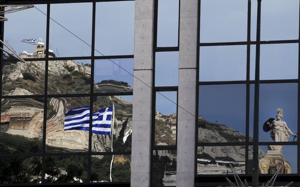 De Griekse vlag weerspiegeld in de ramen van een gebouw in Athene. beeld EPA