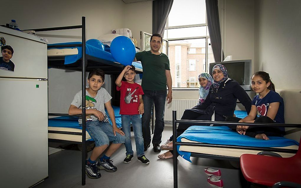 De familie Abrek met hun vier kinderen uit Syrie poseren op hun kamer in het asielzoekerscentrum in Utrecht. Bezoekers kunnen tijdens de open dag een kijkje nemen in het azc. Beeld ANP