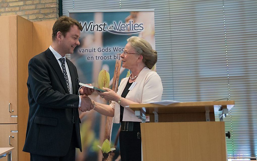 J. Kranendonk-Gijssen overhandigt een jubileumboek aan voorzitter H. J. Koetsier van stichting Winstuitverlies. beeld Inge Joosse