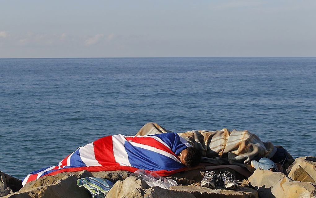 Migranten slapen aan de kust. bij de grens tussen Italië en Frankrijk. beeld AFP