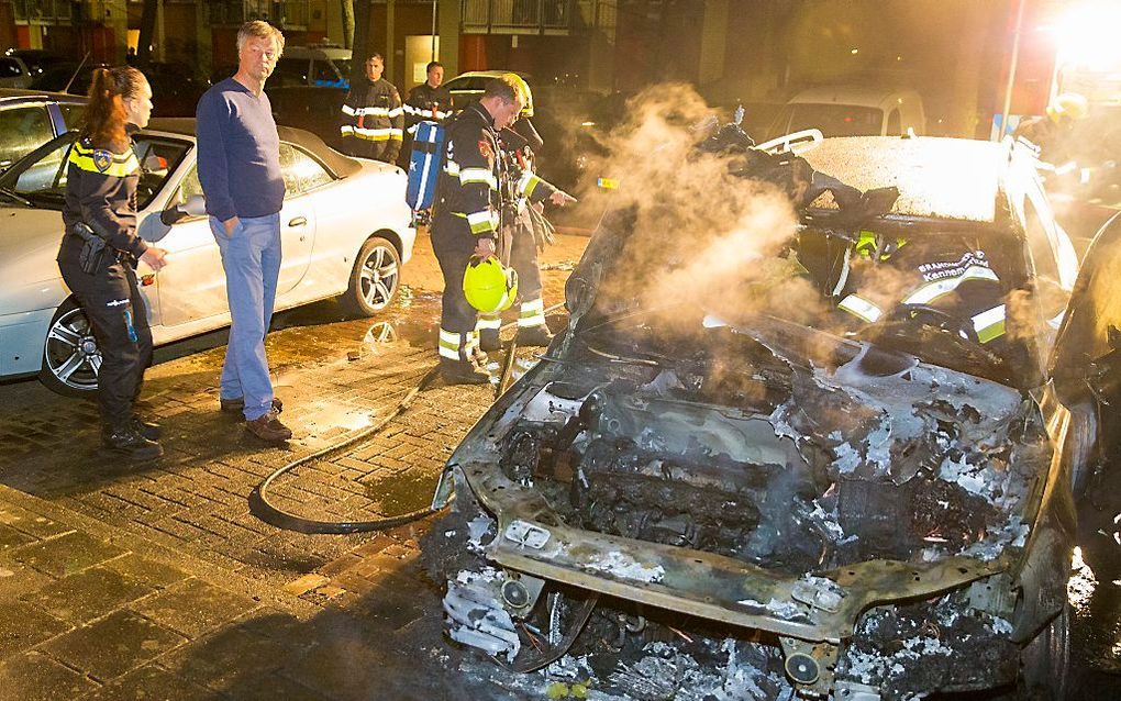 Burgemeester Schneiders van Haarlem bekijkt samen met politie en brandweer zijn auto, die in brand is gestoken. beeld ANP