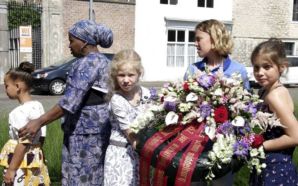 Scholieren van de Algemene Basisschool in Middelburg gisteren met een krans op weg naar het Slavernijmonument op de Balans, waar de Middelburgse slavenhandelaars zetelden. beeld Van Scheyen Fotografie