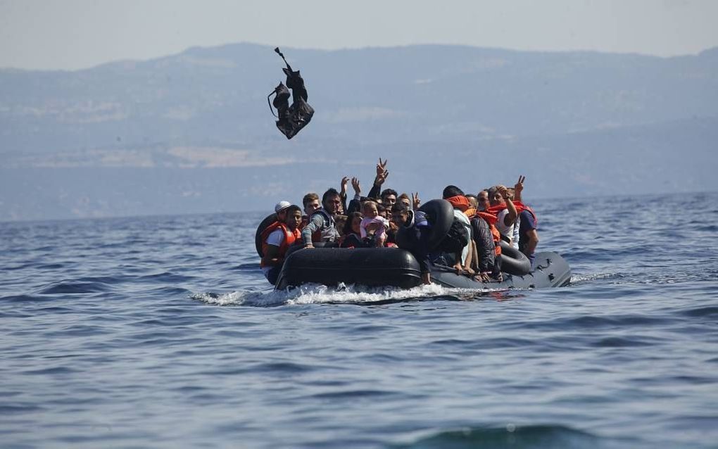 Als de boot bijna het strand raakt, vliegt een zwemvest vrolijk door de lucht. Op het Griekse eiland Lesbos komen dagelijks honderden vluchtelingen aan: meest Syriërs, maar ook Afghanen, Irakezen, Eritreeërs en Somaliërs. beeld Jaco Klamer