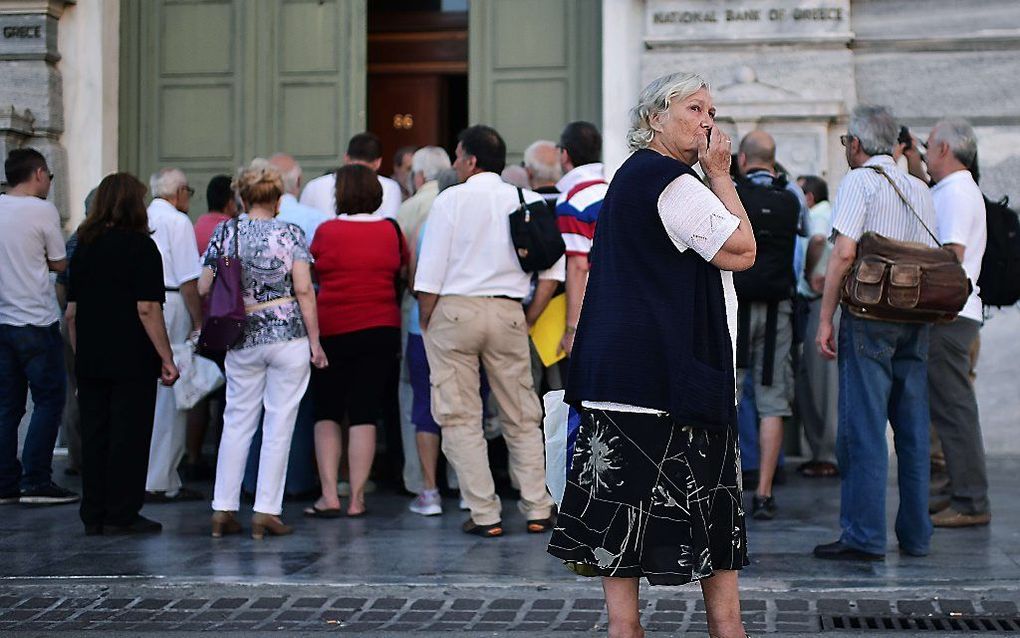 Mensen staan maandag in de rij voor een bank in Athene. Beeld AFP