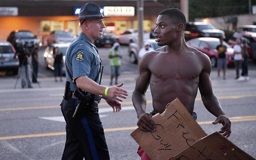 Een agent met een demonstrant in Ferguson. In de Amerikaanse stad zijn inwoners weer de straat op gegaan om te protesteren tegen het politiegeweld jegens zwarte inwoners. beeld EPA