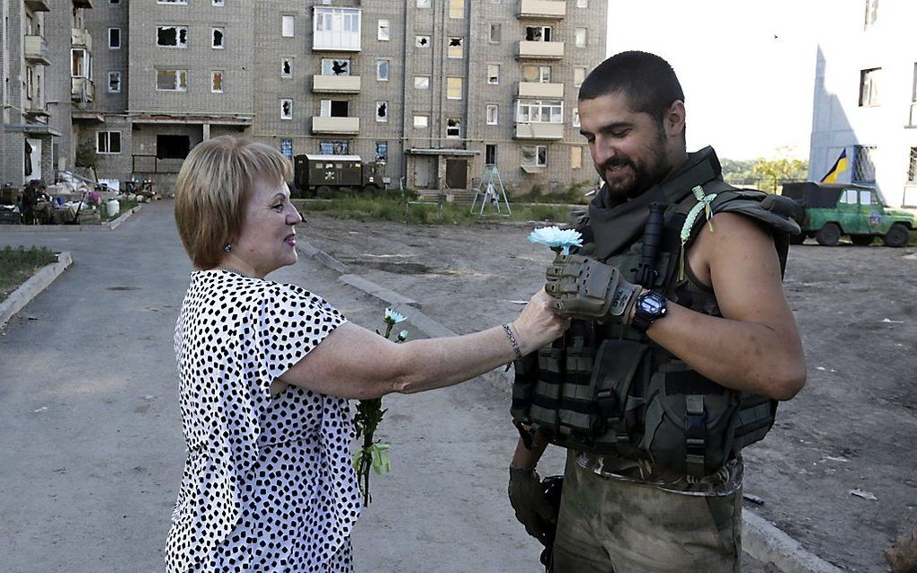 Een vrouw geeft een bloem aan een Oekraïense militair, in de omgeving van Donetsk. beeld AFP