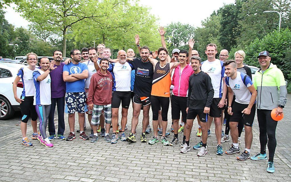 Jan Bakker (in het midden met wit shirt en grijs baardje) met een groep Zwolse hardlopers en Syrische vluchtelingen die in de IJsselhallen verblijven. beeld Jan Bakker