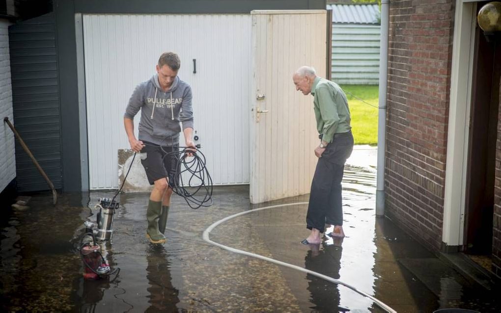 Nico van Wingerden uit Hardinxveld-Giessendam moest maandagmorgen aan de slag om het water uit zijn huis te krijgen. Beeld Cees van der Wal