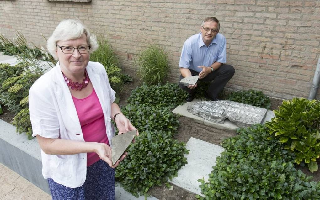 Ineke en Arie Brugmans met een aantal brokstukken van de verdwenen grafsteen in Moerkapelle. Ineke hielp haar man met de reconstructie en het schrijven van het boekje erover. beeld Sjaak Verboom