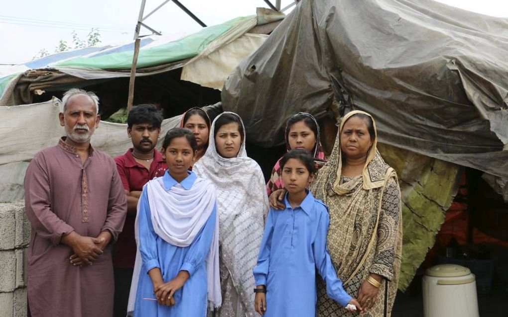 Sadrak en Nasreen met hun kinderen voor hun tent in de sloppenwijk. Beeld SDOK