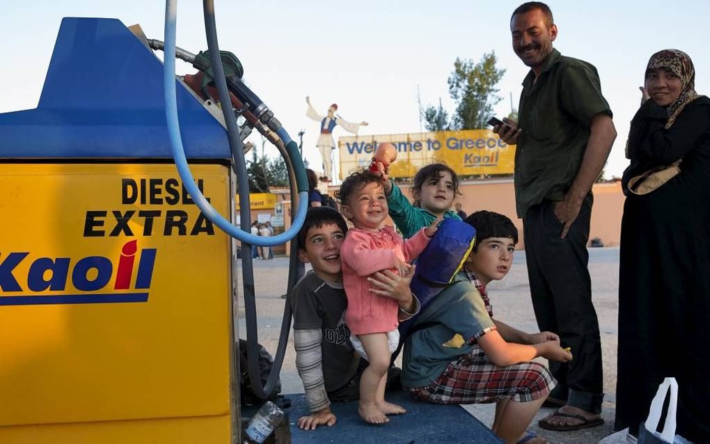 Een Syrisch gezin op de parkeerplaats voor Hotel Hara. Dagelijks zetten bussen uit onder meer Athene hier minimaal duizend vluchtelingen af.  beeld Jaco Klamer