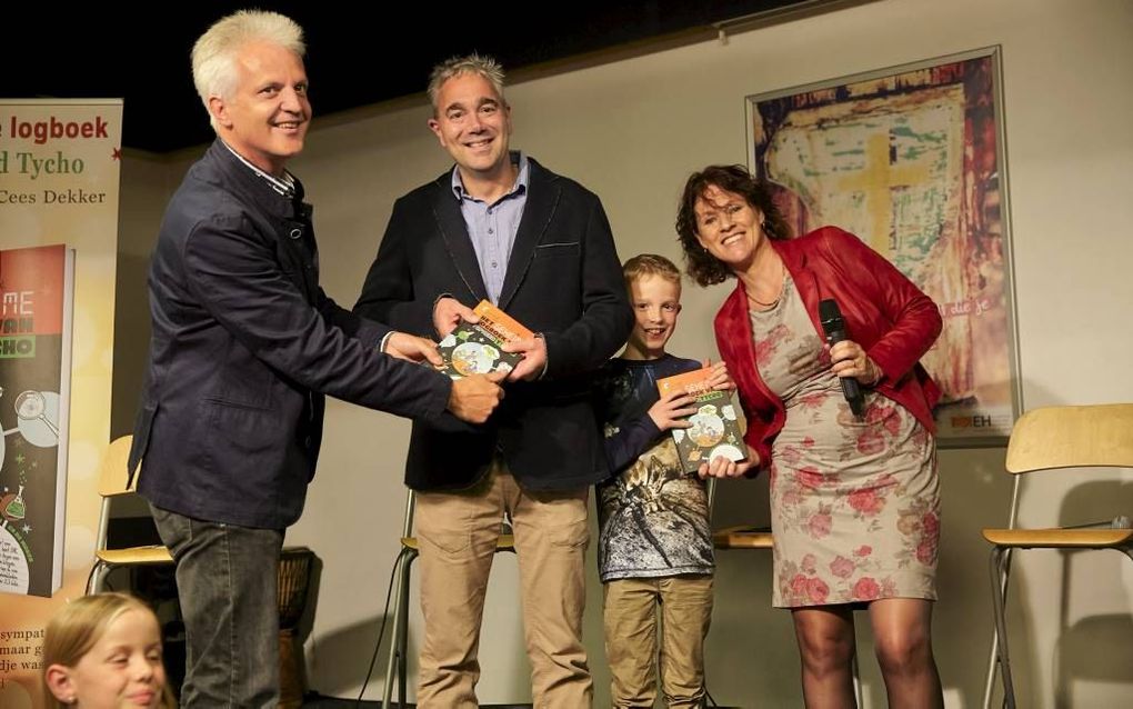 Prof. dr. Cees Dekker (l.) en Corien Oranje (r.) overhandigden donderdag in Amersfoort ”Het geheime logboek van topnerd Tycho” aan dr. ir. Fred Vermolen, een collega van Dekker, en diens zoon Luka. beeld Jaco Klamer