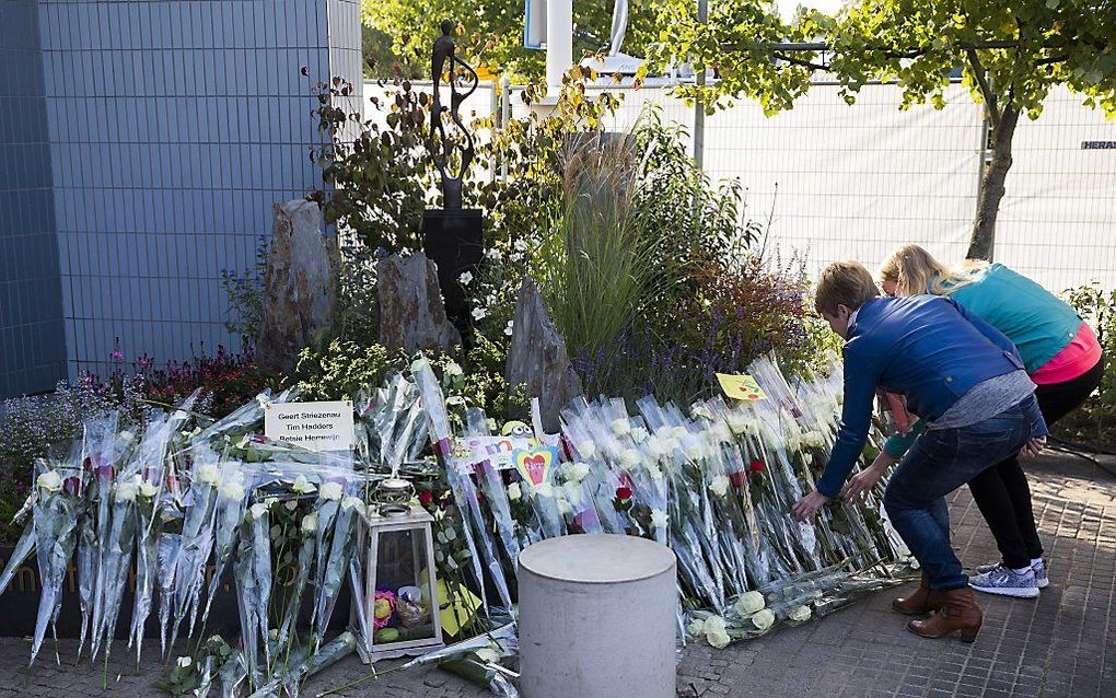 Belangstellenden leggen bloemen bij een sculptuur ter nagedachtenis aan de slachtoffers van het drama met de monstertruck in Haaksbergen. beeld ANP