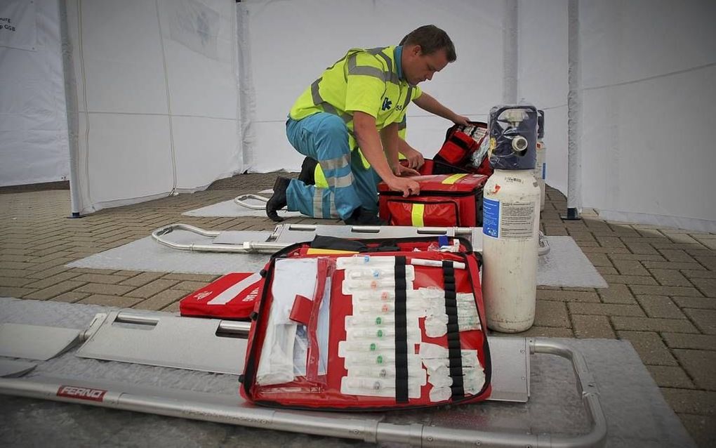 Een ambulanceverpleegkundige zet medische apparatuur paraat voor hulp. Nederland gooit het roer om bij grootschalige rampen met veel slachtoffers. beeld Gerard ten Voorde