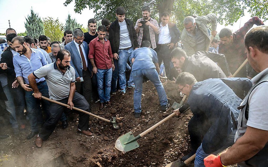 Familieleden en sympathisanten gooien het graf dicht van de pro-Koerdische HDP-kandidaat Erol. Hij kwam zaterdag om door de bomaanslag in de Turkse hoofdstad Ankara, waarbij in totaal 97 mensen omkwamen. beeld AFP