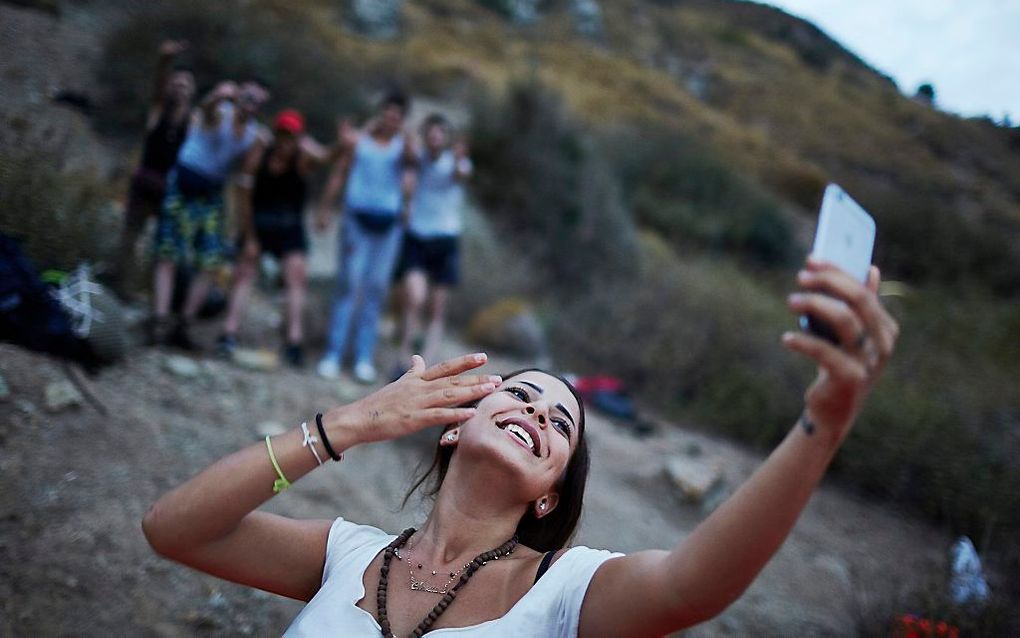 Een vluchtelinge maakt op het Griekse eiland Lesbos een selfie met haar mobieltje. beeld ANP