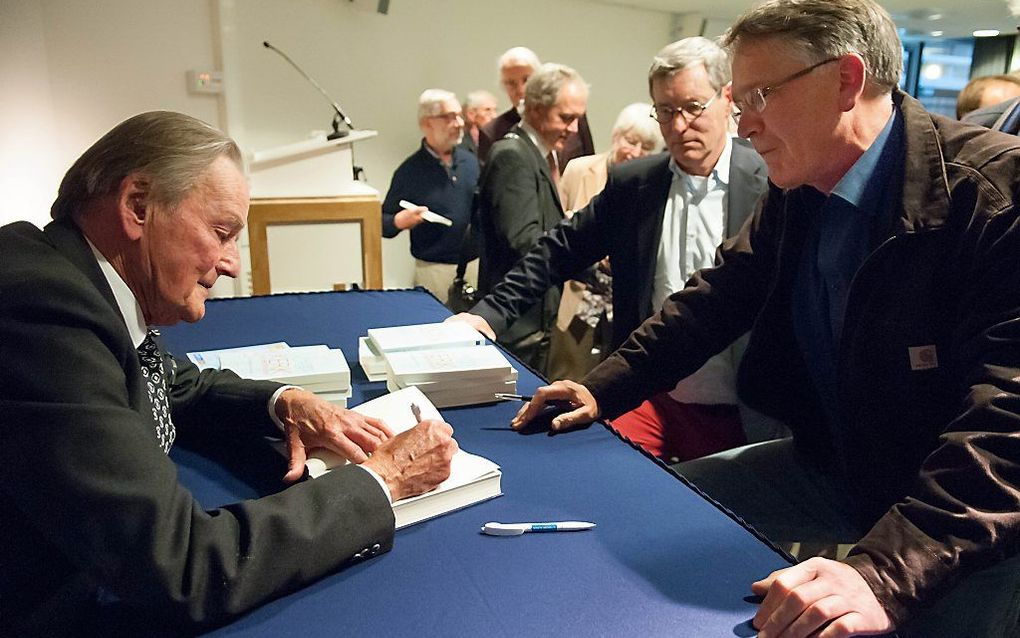 Prof. Harry Kuitert signeert een van zijn boeken.  beeld Ronald Bakker