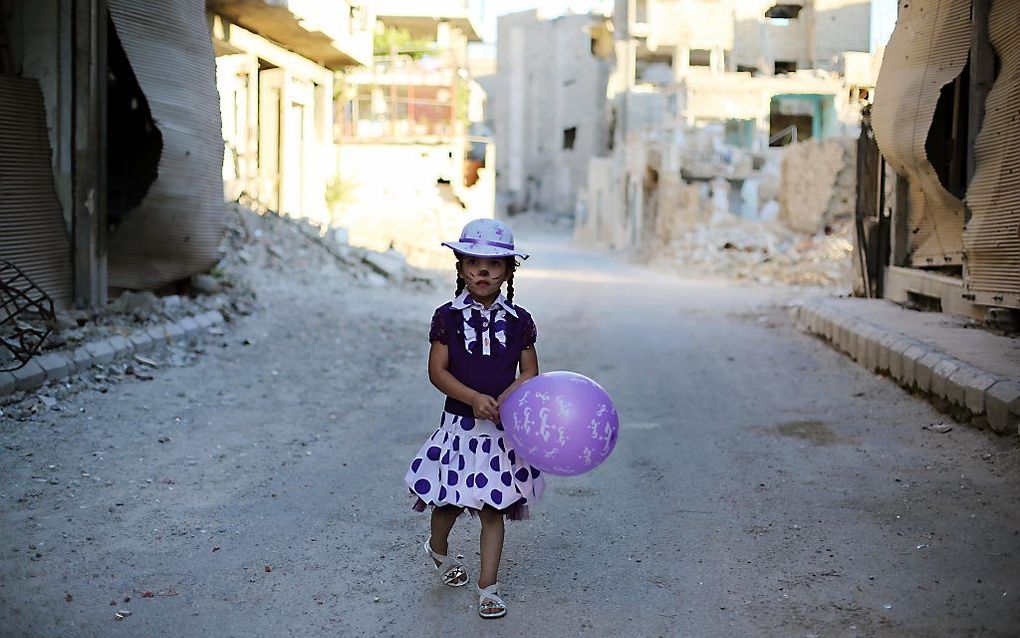 Een geschminkt meisje speelt op straat in een buitenwijk van Damascus. beeld AFP