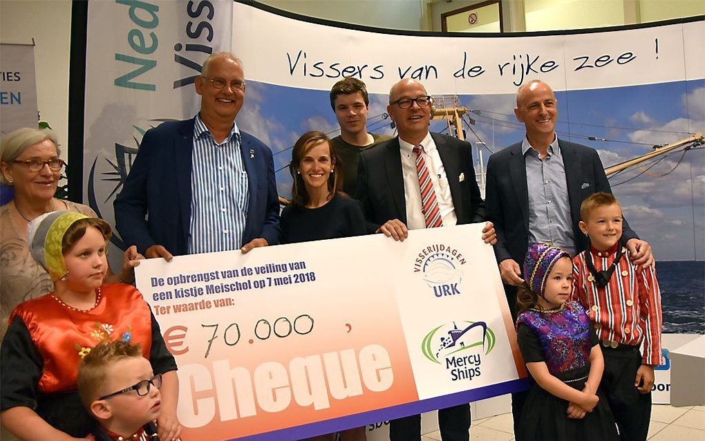 Voorzitter Klaas-Jelle Koffeman van de Stichting Visserijdagen Urk (l) overhandigt een cheque met de opbrengst van de veiling van de eerste mei-schol aan interim-directeur Marianne Huurman van Mercy Ships.  Rechts directeur Jelle van Veen van visverwerken