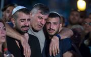 De vader en broer van de zondag gedode politieman Yosef Kirme tijdens diens begrafenis op Mount Herzl in Jeruzalem. Kirme werd zondag gedood bij een aanslag vanuit een auto. beeld EPA, Jim Hollander