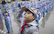 Chinese kinderen krijgen les in de begroetingsceremonie van de vlag. beeld AFP