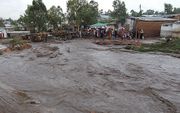 Dorpelingen kijken naar hun overstroomde straat. beeld AFP, Bonex Julius