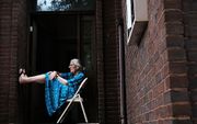 Een oudere Amerikaanse dame op de stoep van haar woning in Philadelphia, waar deze week de conventie van de Democraten plaatsvindt. beeld AFP
