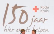 Koning Willem-Alexander ontvangt uit handen van Rode Kruisvrijwilliger Jordi Rijsdam het eerste exemplaar van het jubileumboek ”Hier om te helpen", tijdens de viering van 150 jaar Nederlandse Rode Kruis. beeld ANP