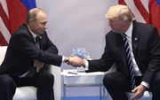 Trump (r.) en Poetin schudden elkaar de hand. beeld AFP