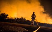 Een brandweerman bestrijdt de vlammenzee bij Los Angeles. beeld AFP