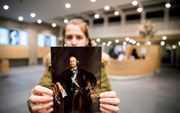 Een museummedewerkster houdt een portret op van Johan Maurits. beeld ANP, Jerry Lampen
