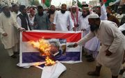 Pakistani verbranden een Nederlandse vlag met een afbeelding van Wilders. beeld EPA, Shahzaib Akber