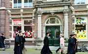 Hoogleraren lopen langs de ingang van de Theologische Universiteit in Kampen. beeld RD