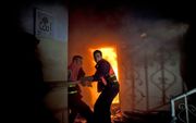 Palestijnse brandweermannen proberen een gebombadeerd flatgebouw te blussen. Foto EPA