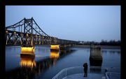 De brug bij de Chinese grensstad Dandong verbindt China met Noord-Korea. Halverwege houdt de verlichting op en begint het deel dat de Noord-Koreanen onderhouden. Toeristen turen er met kijkers naar de overkant. Beeld Henk Visscher