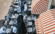 Vijfentwintig theologen en een verslaggever bogen zich maandag over het schaakbord op het zonnige terras van het chique Manor Hotel in Amsterdam tijdens het dertiende NK voor Pastores. beeld Ronald Bakker