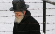Een Joodse man loopt achter het prikkeldraad van het voormalige concentratiekamp Auschwitz-Birkenau.  beeld RD