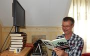 Meester Van den Dool uit Doetinchem spreekt in zijn woonkamer kinderboeken in om kinderen weer te laten genieten van tekst. beeld RD