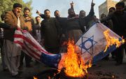 Palestijnse demonstranten verbranden een vlaggen van Israël en de VS. beeld AFP