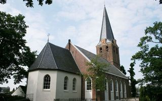 Oude bakstenen kerk met witte uitbouw.